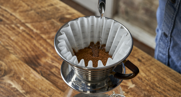 Kaffeepulver in Kalita Handfilter mit Kalita Papierfilter wird aufgegossen