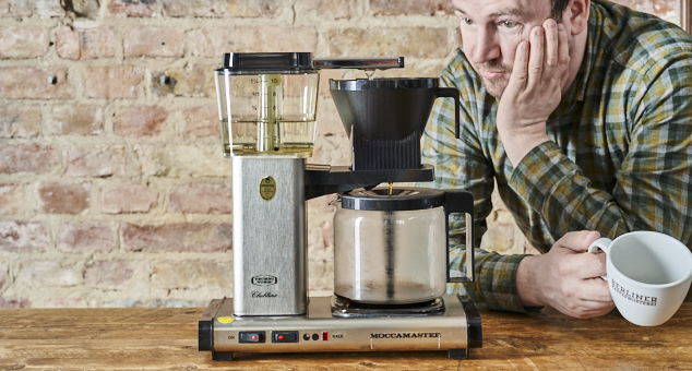 Mann wartet gespannt auf Kaffee aus einer Kaffeemaschine mit Berliner Kaffeerösterei Kaffeetasse