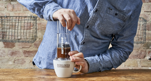 Mann press mit eigener Körperkraft den Zylinder der Aeropress nach unten