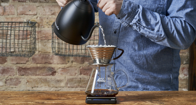 Mann gießt heißes Wasser durch Kalita Handfilter mit Kalita Papierfilter