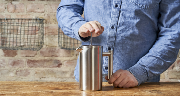 Ein Mann drückt den Stempel seiner Edelstahl French Press runter