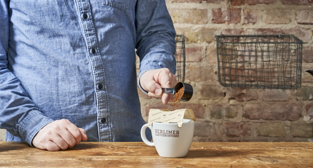 Mann füllt Kaffeepulver in Aufgussbeutel von Kalita